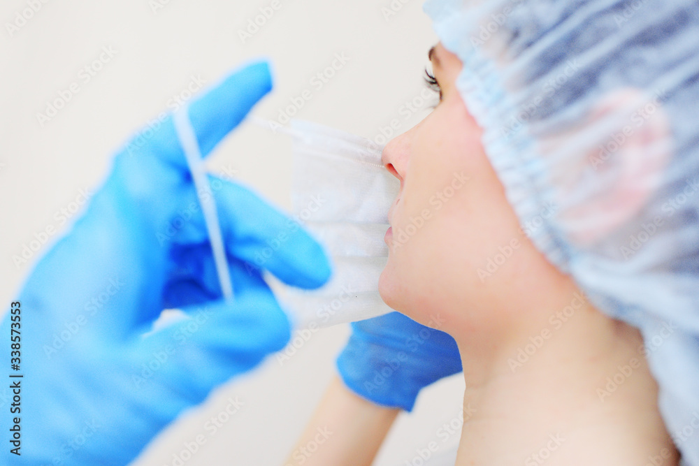 a young woman doctor or nurse in rubber gloves puts on a medical mask on a light background. a young woman doctor or nurse in rubber gloves puts on a medical mask on a light background.