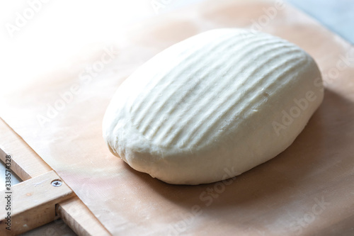 Homemade bread. Ball of raw dough on wooden board on white background.