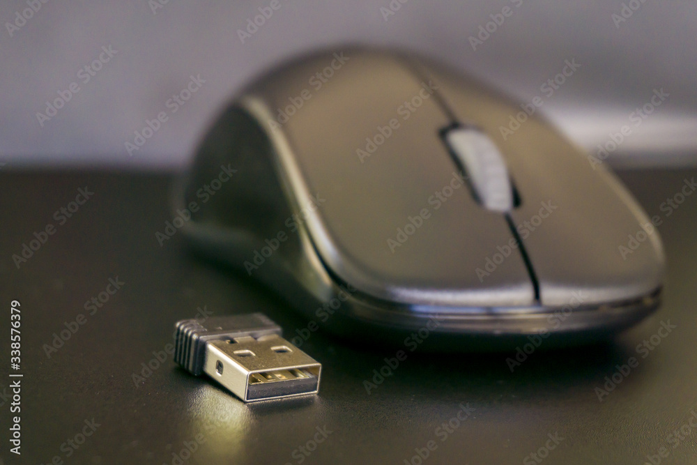 Close up of black wireless laptop mouse with USB transciever device. Computer accessories, wireless technology and portability concept. 
