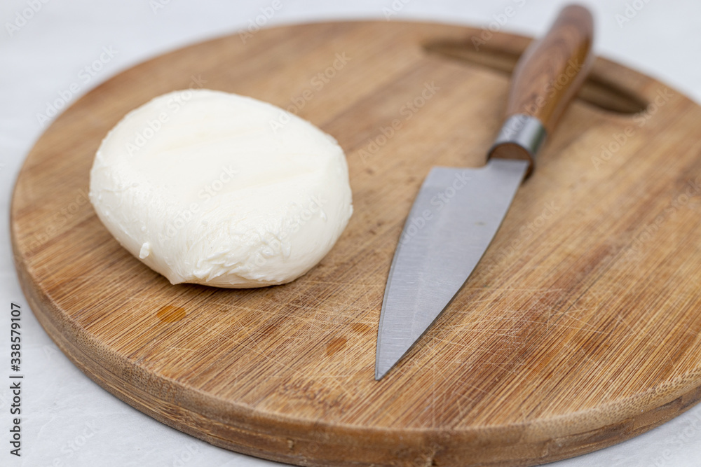 Mozarella cheese on the cutting wooden board with knife Mozarella cheese on the cutting wooden board with knife