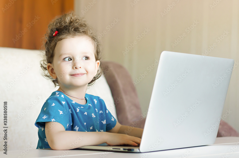 pleased and happy girl smiles and plays at the computer, laptop. preschool classes of children online. Distance learning online education. pleased and happy girl smiles and plays at the computer, laptop. preschool classes of children online. Distance learning online education.