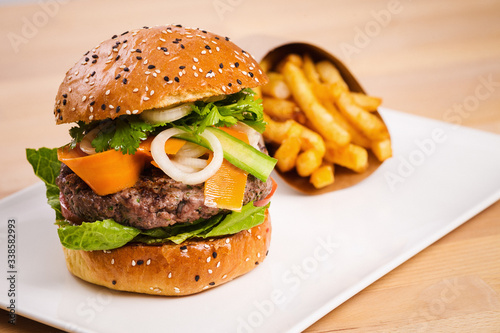 Healthy homemade beef burger with veggies. Potato fries on the side. Perfect concept for burger place and delivery promotion.