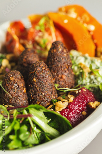 Delicious healthy salad with falafel and dried tomatoes. For healthy living. Perfect for takeaway and delivery. Vegan food photography focus view.