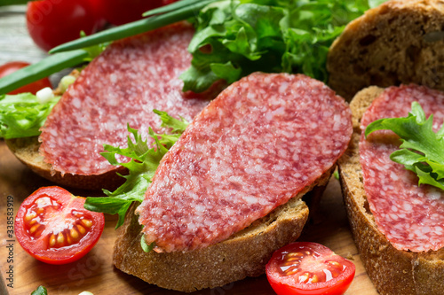 Appetizer of fresh sandwiches with sausage, tomatoes and herbs.