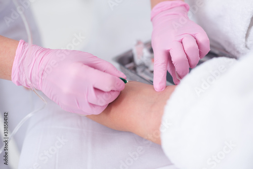 doctor in pink gloves at the clinic injects patient medicine against 
Covid-19  for recovery. botox injection. cosmetology, doctor, injection. A nurse in pink gloves holds a syringe in his hand 