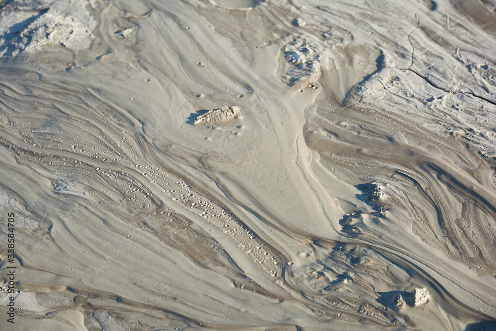 Fototapeta premium Mud flow from a mud volcano. Cracked mud surface. Mudflow texture with cracks.