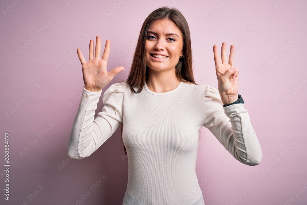Young beautiful woman with blue eyes wearing casual white t-shirt over pink background showing and pointing up with fingers number eight while smiling confident and happy. Young beautiful woman with blue eyes wearing casual white t-shirt over pink background showing and pointing up with fingers number eight while smiling confident and happy.
