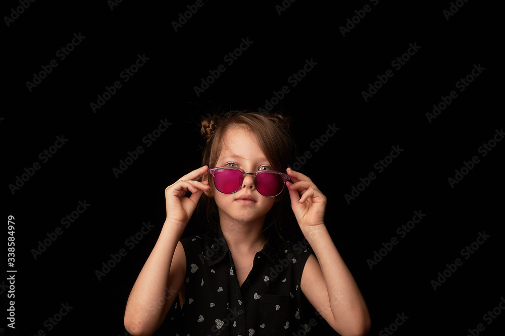 Obraz premium A girl of 6 years in pink glasses. Childhood, naive view of the world.