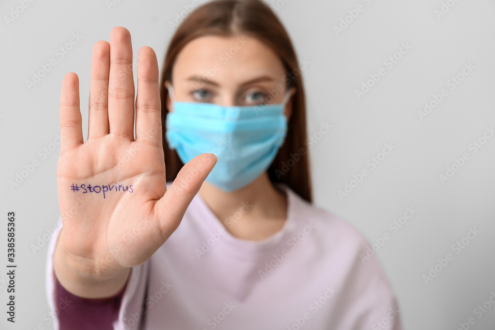 Woman in protective mask showing her palm with written text on grey background. Concept of Coronavirus epidemic Woman in protective mask showing her palm with written text on grey background. Concept of Coronavirus epidemic