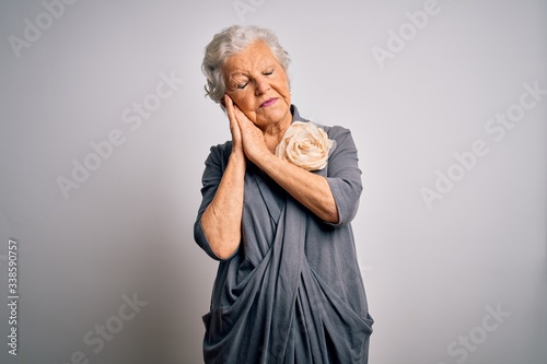 Senior beautiful grey-haired woman wearing casual dress standing over white background sleeping tired dreaming and posing with hands together while smiling with closed eyes.