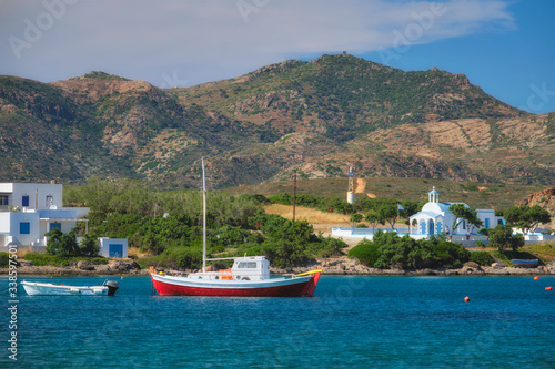 The beach and fishing village of Pollonia with fishing boats in sea and church. Pollonia town, Milos island, Greece photo