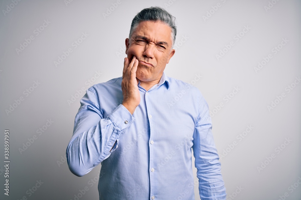 Middle age handsome grey-haired business man wearing elegant shirt over white background touching mouth with hand with painful expression because of toothache or dental illness on teeth. Dentist Middle age handsome grey-haired business man wearing elegant shirt over white background touching mouth with hand with painful expression because of toothache or dental illness on teeth. Dentist