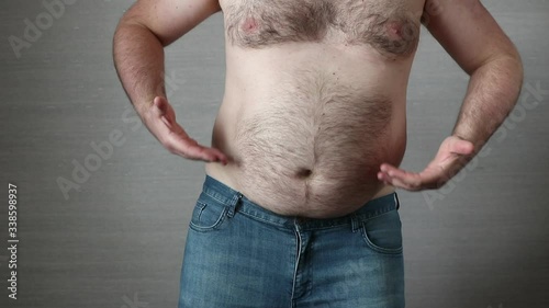 Happy shirtless fat man in jeans dancing and his big obese belly shaking. Overeating problem concept