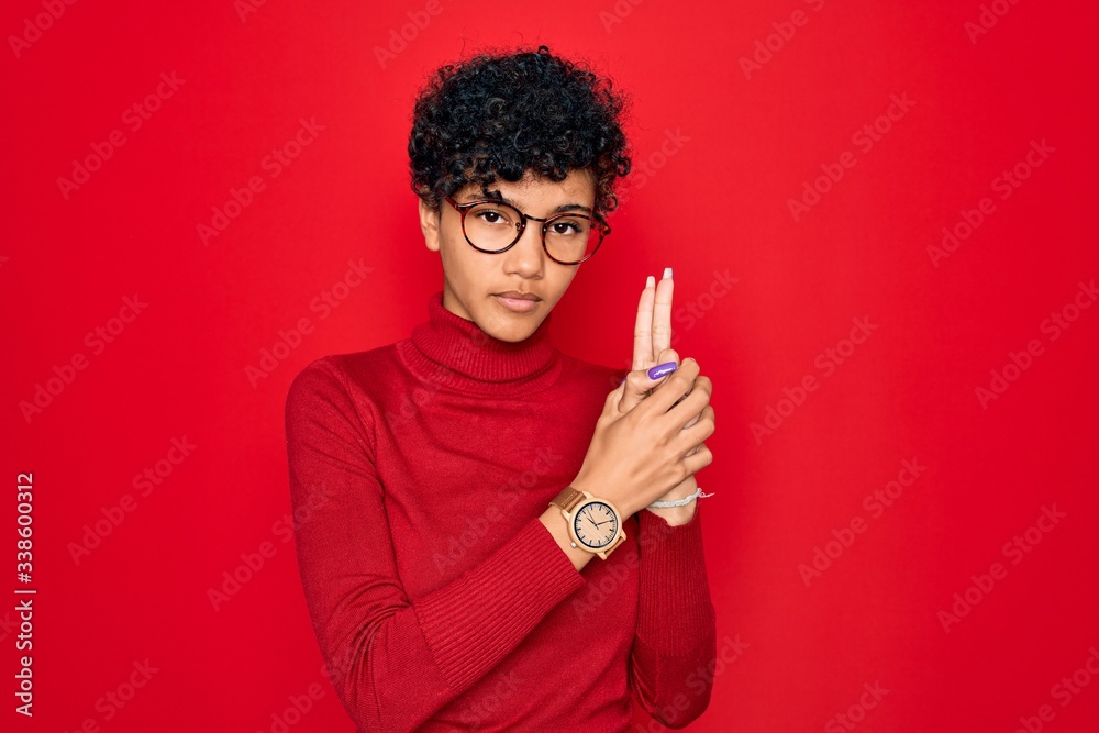 Young beautiful african american afro woman wearing turtleneck sweater and glasses Holding symbolic gun with hand gesture, playing killing shooting weapons, angry face Young beautiful african american afro woman wearing turtleneck sweater and glasses Holding symbolic gun with hand gesture, playing killing shooting weapons, angry face