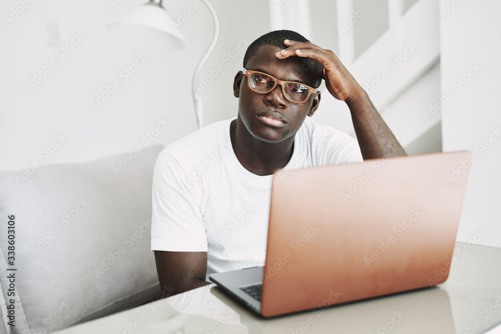 A man of African appearance at home in front of a laptop