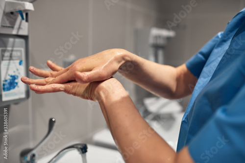 Close-up of a doctor washing his hands using a disinfectant dispenser.
