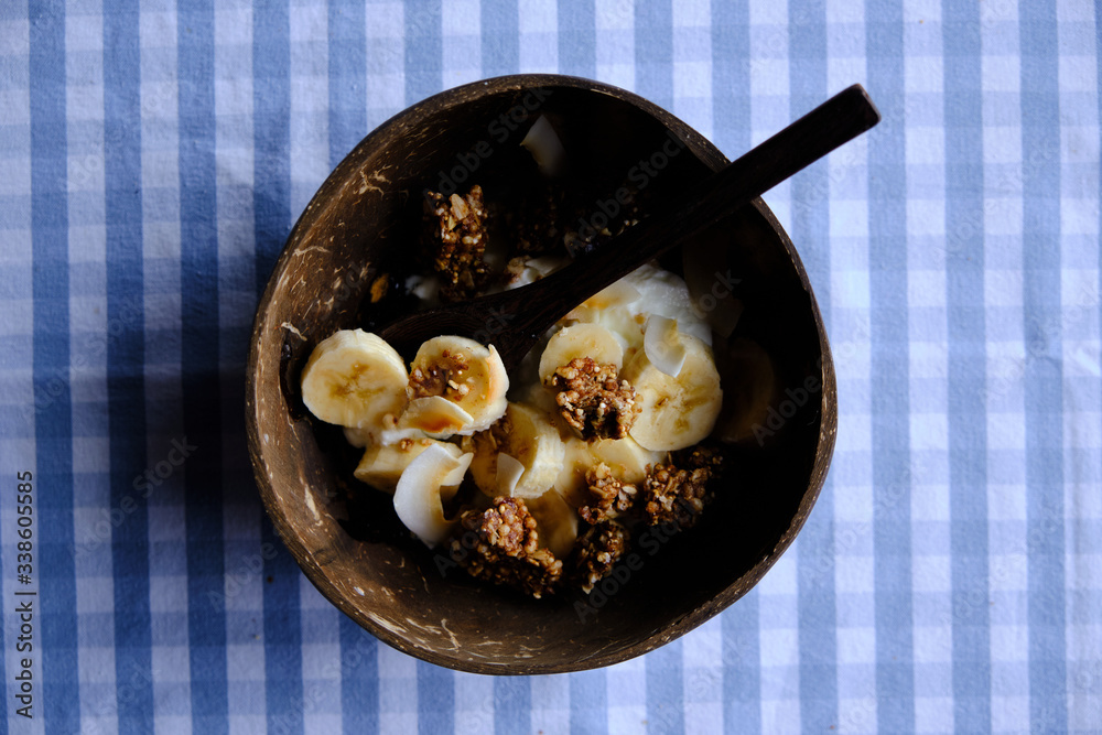 yoghurt with banana slices, coconut and granola, healthy snack in coconut bowl yoghurt with banana slices, coconut and granola, healthy snack in coconut bowl