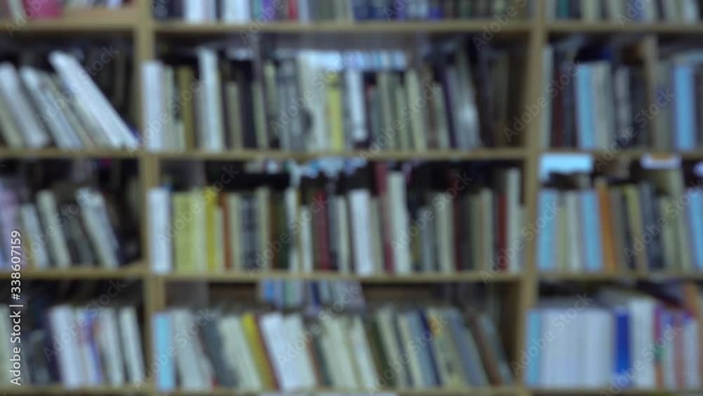 Blurred view of books on a wooden shelf at library