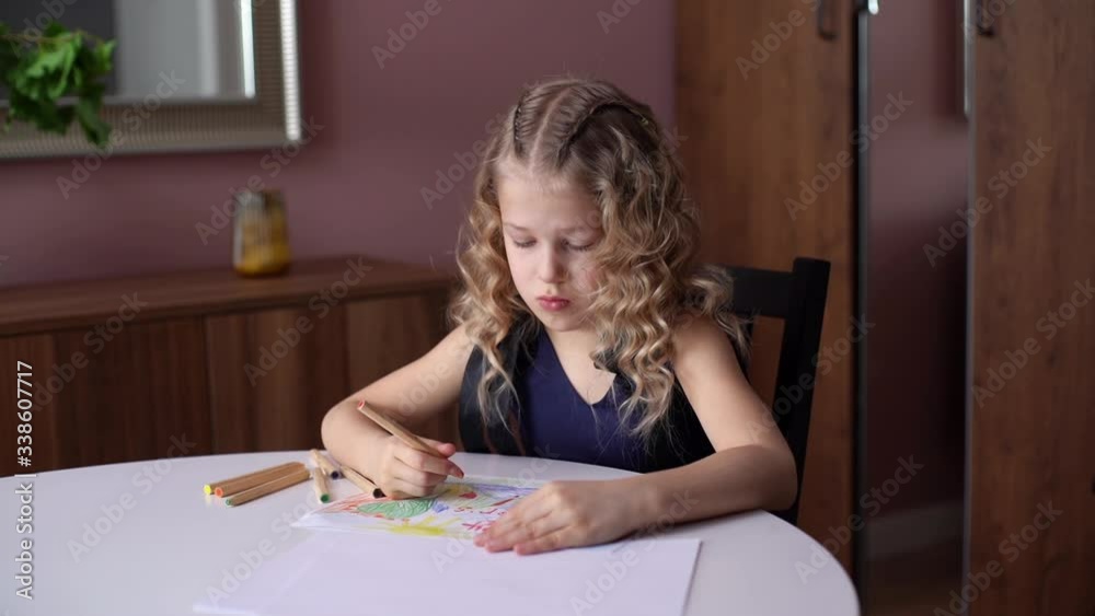 Adorable happy little girl drawing with pencils at the home at the white table in cozy childs room. Concept of child creative activity. Shooting in slow motion. Adorable happy little girl drawing with pencils at the home at the white table in cozy childs room. Concept of child creative activity. Shooting in slow motion.