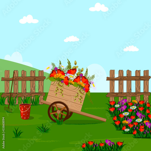 Wooden cart with flowers in the flowerbed