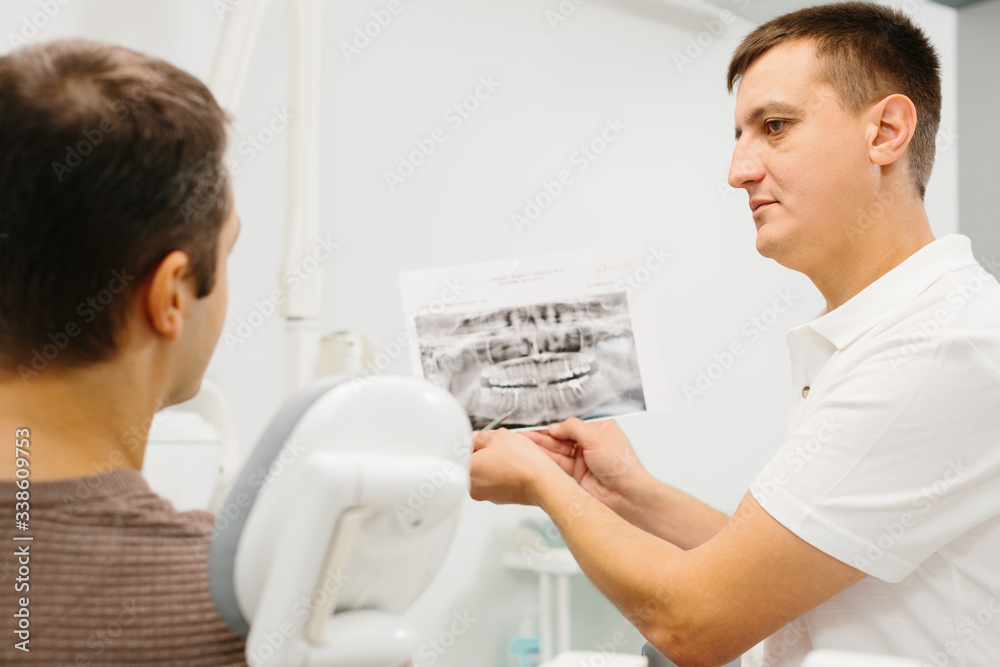 Obraz premium Dentist shows a patient x-ray of teeth
