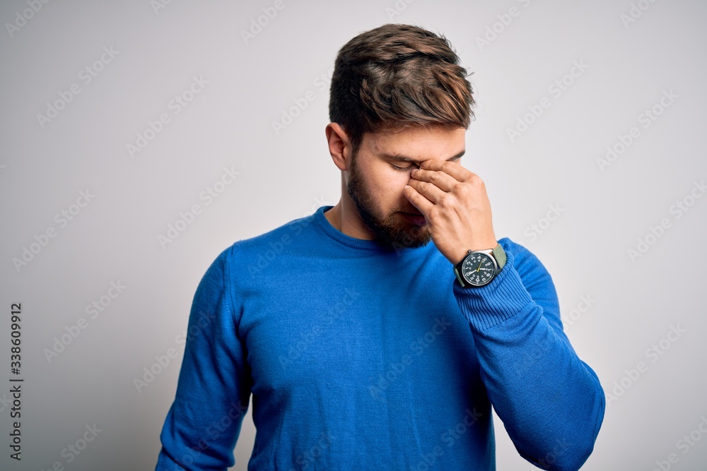 Young handsome blond man with beard and blue eyes wearing casual sweater tired rubbing nose and eyes feeling fatigue and headache. Stress and frustration concept. Young handsome blond man with beard and blue eyes wearing casual sweater tired rubbing nose and eyes feeling fatigue and headache. Stress and frustration concept.