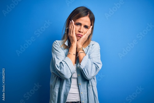 Middle age beautiful woman wearing casual shirt standing over isolated blue background Tired hands covering face, depression and sadness, upset and irritated for problem