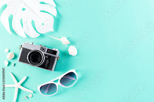 Retro film camera, sunglasses, starfish and sea shell on green pastel background for summer holiday and vacation concept.