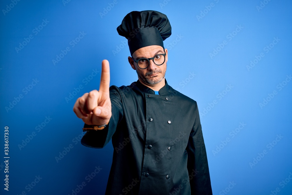 Young handsome chef man wearing cooker uniform and hat over isolated blue background Pointing with finger up and angry expression, showing no gesture Young handsome chef man wearing cooker uniform and hat over isolated blue background Pointing with finger up and angry expression, showing no gesture
