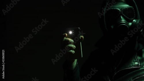 A man in mask flashing the light on the camera, searching for way out, hearing the alarm.Man with flashlight in danger zone.Alarm! Flashing white light.Apocalypse. photo