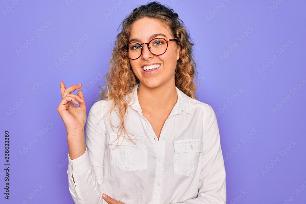 Young beautiful woman with blue eyes wearing casual shirt and glasses over purple background with a big smile on face, pointing with hand and finger to the side looking at the camera. Young beautiful woman with blue eyes wearing casual shirt and glasses over purple background with a big smile on face, pointing with hand and finger to the side looking at the camera.