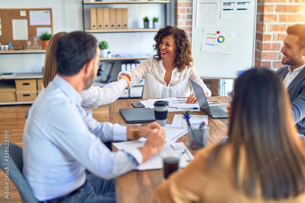 Group of business workers smiling happy and confident. Working together with smile on face shaking hands at the office Group of business workers smiling happy and confident. Working together with smile on face shaking hands at the office