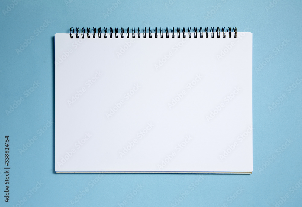 Blank spiral notebook isolated on blue background Blank spiral notebook isolated on blue background