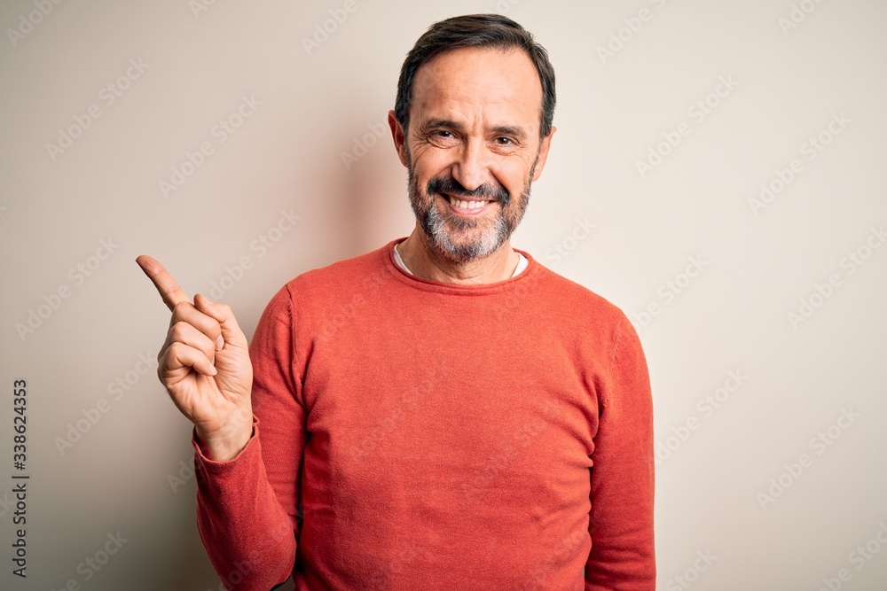 Middle age hoary man wearing casual orange sweater standing over isolated white background with a big smile on face, pointing with hand finger to the side looking at the camera. Middle age hoary man wearing casual orange sweater standing over isolated white background with a big smile on face, pointing with hand finger to the side looking at the camera.