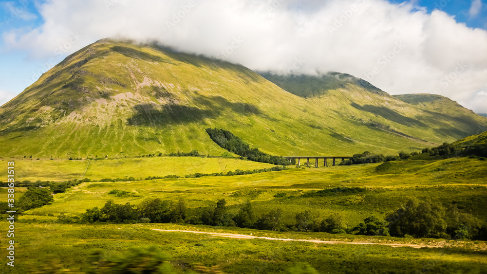 Dirt road follows stream into rolling green hills Dirt road follows stream into rolling green hills