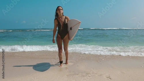 Ocean surf. Beautiful young surfer girl running across the blue sea beach with surfboard to the water. Sun shining bright. Summer vacation on exotic island. Sport outdooor activity and travel concept. photo