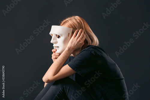Woman holding mask on dark ...