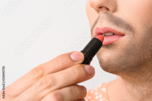 Young transgender woman with lipstick on white background, closeup