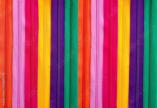 Background of colorful pattern zippers in orange, pink, red, yellow, green and dark purple.