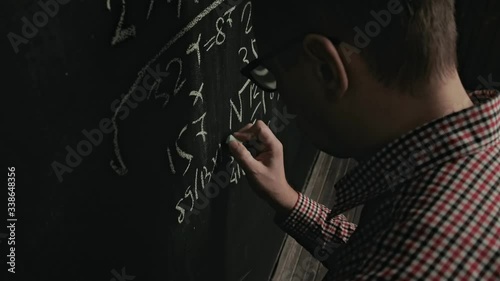 man writes math formula on blackboard