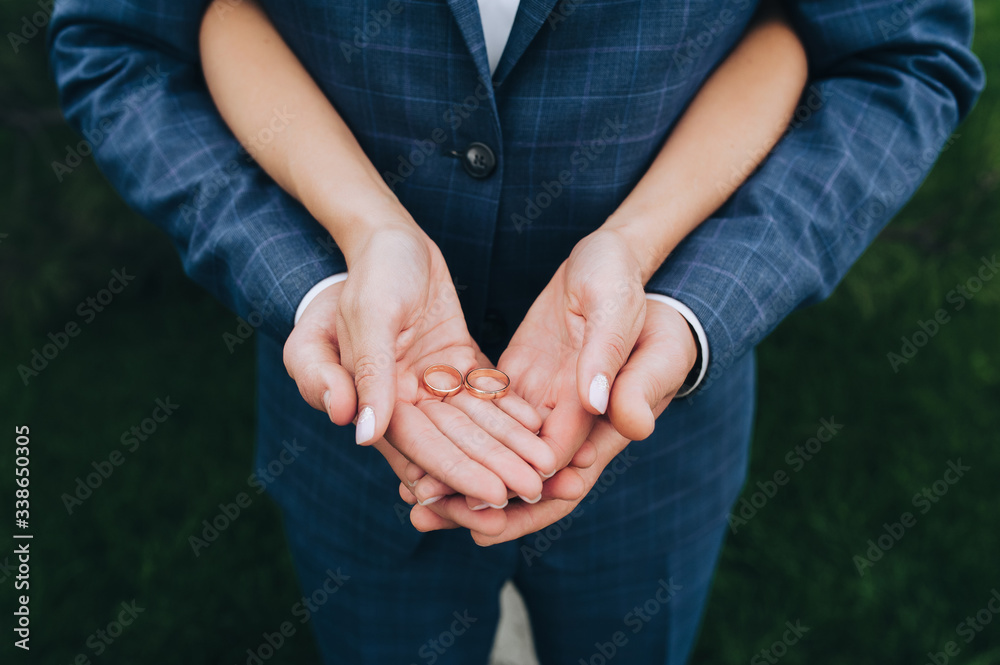 The newlyweds are holding in their hands, on their palms, gold wedding rings close-up. Bride and groom on nature. Concept of marriage. The newlyweds are holding in their hands, on their palms, gold wedding rings close-up. Bride and groom on nature. Concept of marriage.