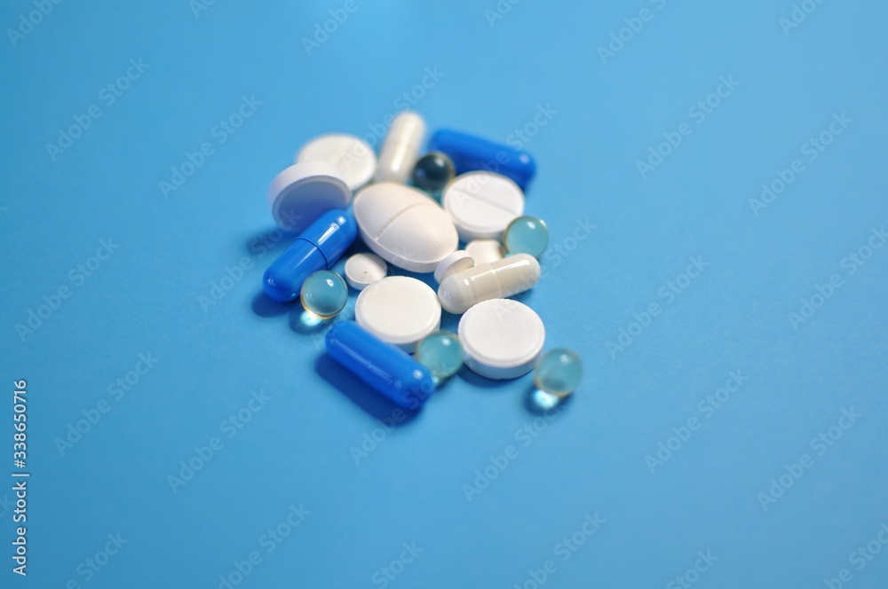 Colorful pills scattered on blue table. Medicine against COVID-19 and diseases