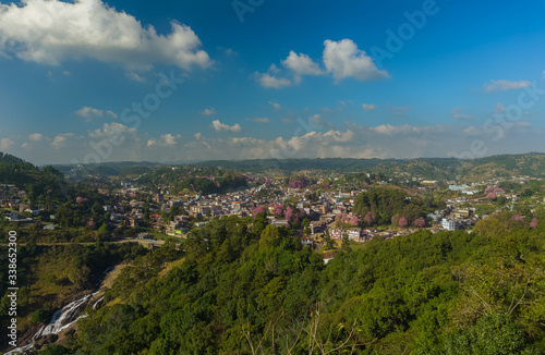 A small town during the clear sky day with cherry blossom and waterfall