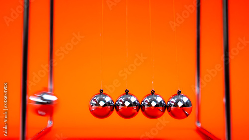 Newtons cradle metal balls moving on orange background