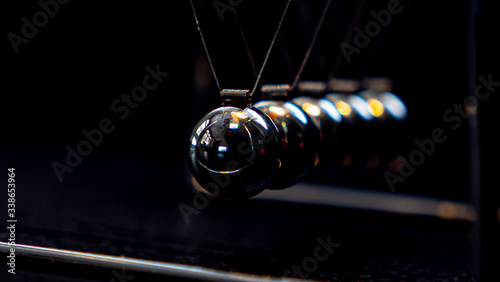 Newtons cradle metal ball moving on black background