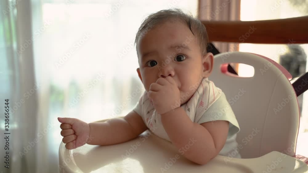 happy asian baby feeding time sitting on highchair happy asian baby feeding time sitting on highchair