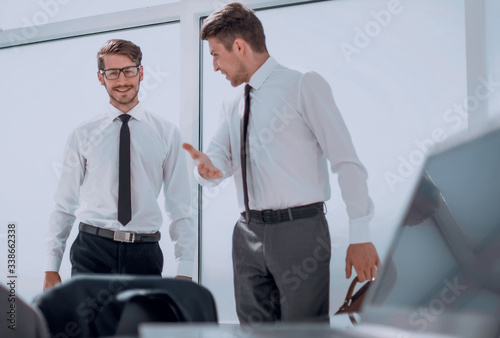 Two businessmen shaking hands standing at big window