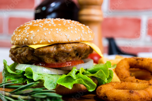 Homemade fresh tasty hamburger side dish with tomato, french fries, ketchub, mastard, salt and pepper on wood plate with white wooden plank background photo