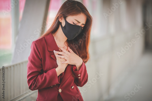 Asian woman wearing mask for protect pm2.5 and cough with Covid-19 virus outbreak in public. But her with severe coughing and chest pain.