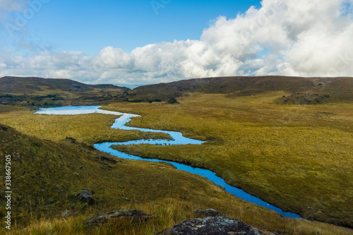 amazing landscape in the countryside with a stream flowing by and a vista view of the clouds and the mountains